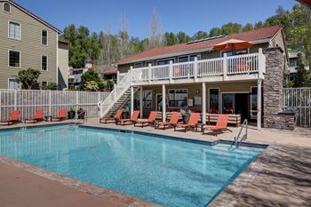 a swimming pool with orange chairs in front of the resident clubhouse at 2000 Lake Washington Apartments, Renton, WA